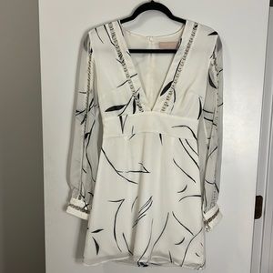 White mini dress with blue design. Sheer sleeves with cut out detailing.